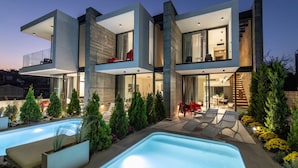 Una casa moderna a due piani con piscina, area relax esterna e giardino curato.