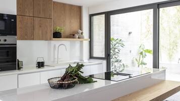 Eine moderne Küche mit Kochinsel, Holzschränken und einem großen Fenster, das für natürliches Licht sorgt.