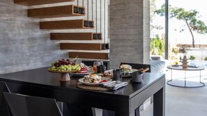 Un'area pranzo moderna con un tavolo lungo, sedie nere e una mensola in legno fissata al muro.