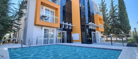 A modern building with a swimming pool in front.