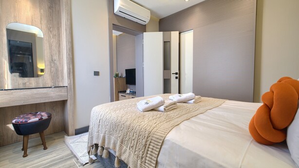 Ein modernes Hotelzimmer mit einem großen Bett, einem Flachbildfernseher, einem Spiegel und einer Klimaanlage.