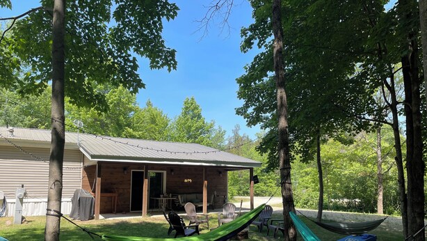 Eine Holzhütte mit Veranda, Sitzgelegenheit im Freien und einer Hängematte.