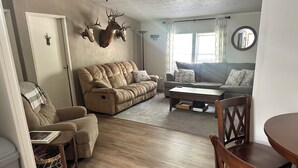 Ein Wohnzimmer mit Sofa, Sessel, Couchtisch und einem Esstisch mit Stühlen.