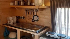 A compact kitchen with wooden walls, a small sink, a coffee maker, and a compact refrigerator. - Prive Jacuzzi, Cows, Dairyfarm, Relaxing, Sleeping (Hitzum)