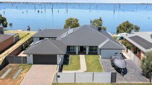 Et moderne hus med to etager, en garage, solpaneler og udsigt til et stort vandareal.