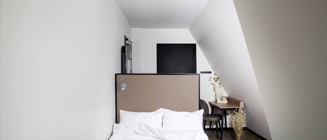 Un dormitorio con una cama, un escritorio y una silla.
