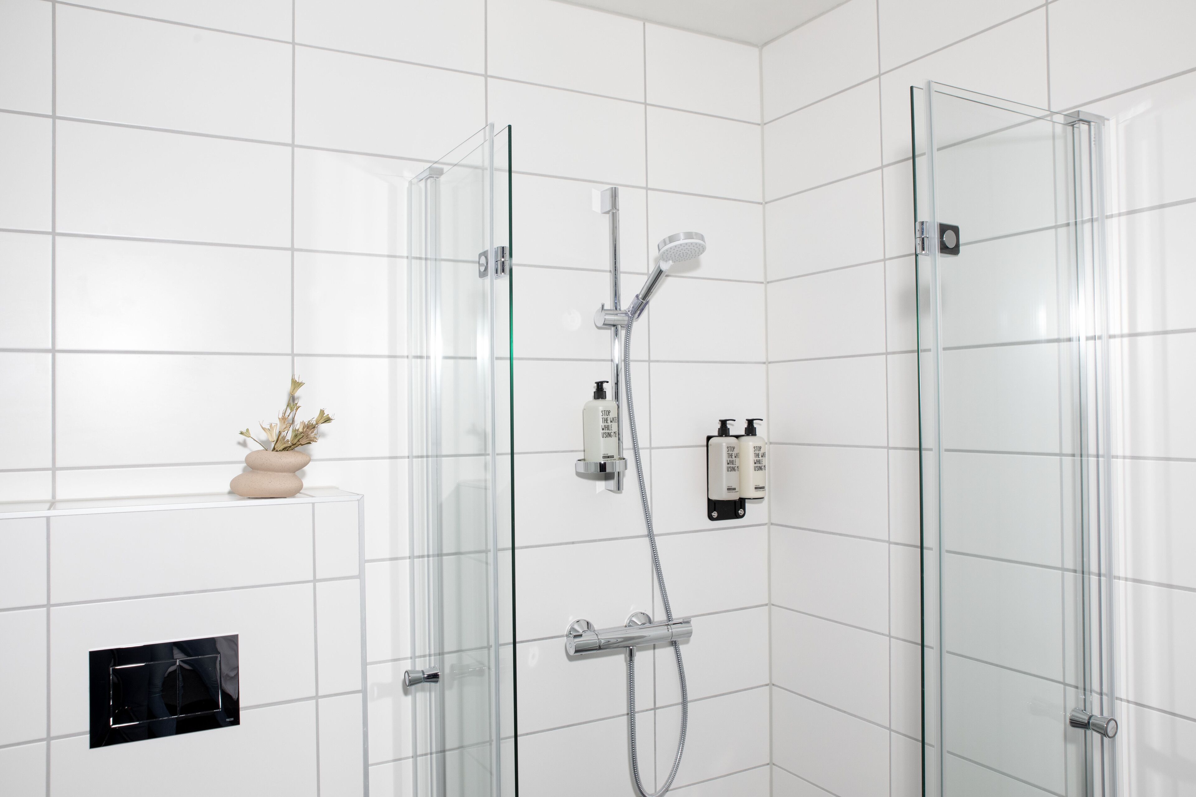 Un baño moderno con ducha de vidrio, calefacción integrada y una pequeña planta en la pared.