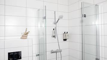 Un baño moderno con ducha de vidrio, calefacción integrada y una pequeña planta en la pared.