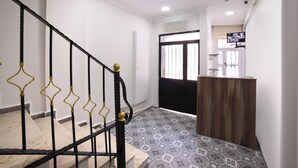 A staircase with black and gold railings, a patterned floor, and a wooden counter in a hallway. - Seven Roses Apart Hotel (Istanbul)