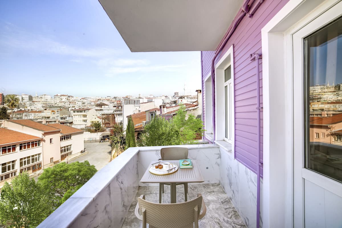 Varanda com mesa e cadeiras, com vista para a paisagem urbana.