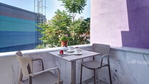 A balcony with a table set for two, a potted plant, and a view of a building. - Seven Roses Apart Hotel (Istanbul)