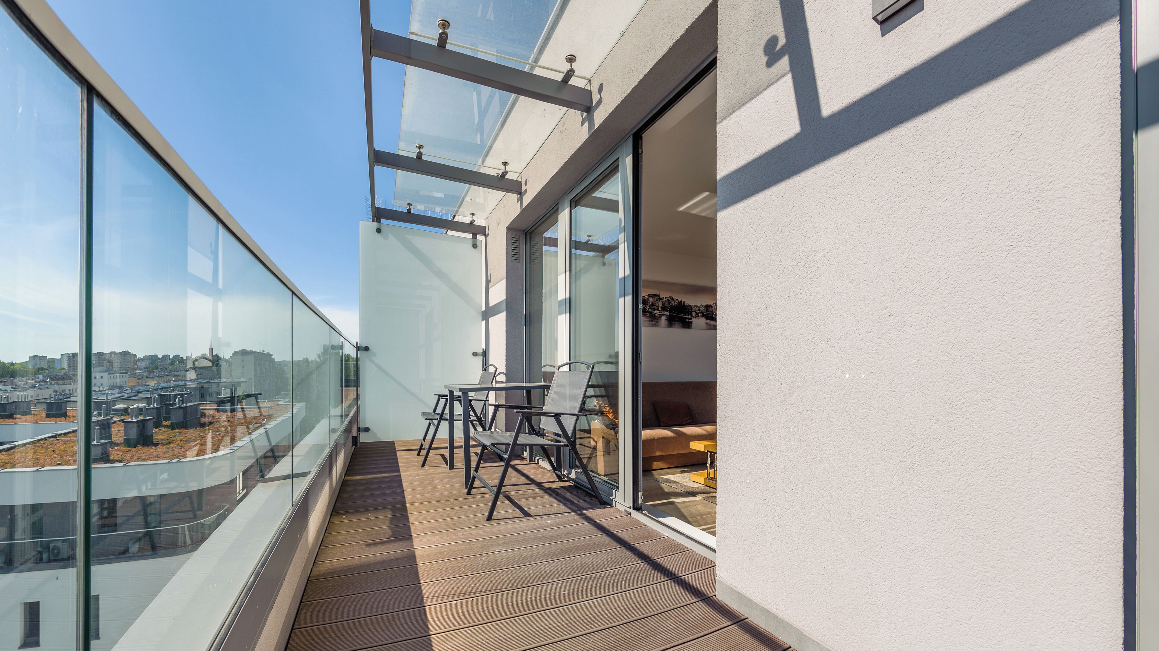 Ein Balkon mit Blick auf die Stadt, einem Tisch mit Stühlen und einer Couch.
