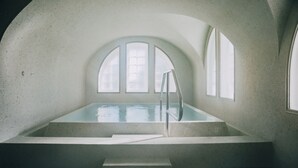 A large indoor swimming pool with arched windows and a ladder leading into the water. - Slottsholmen hotell och restaurang (Vastervik)