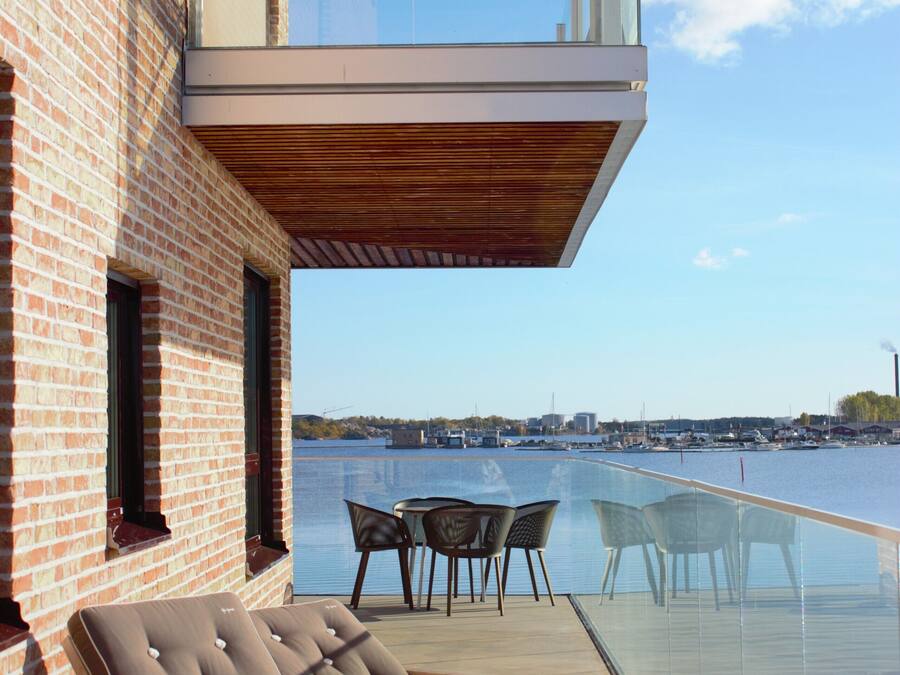 A modern building with a glass balcony overlooking a body of water.