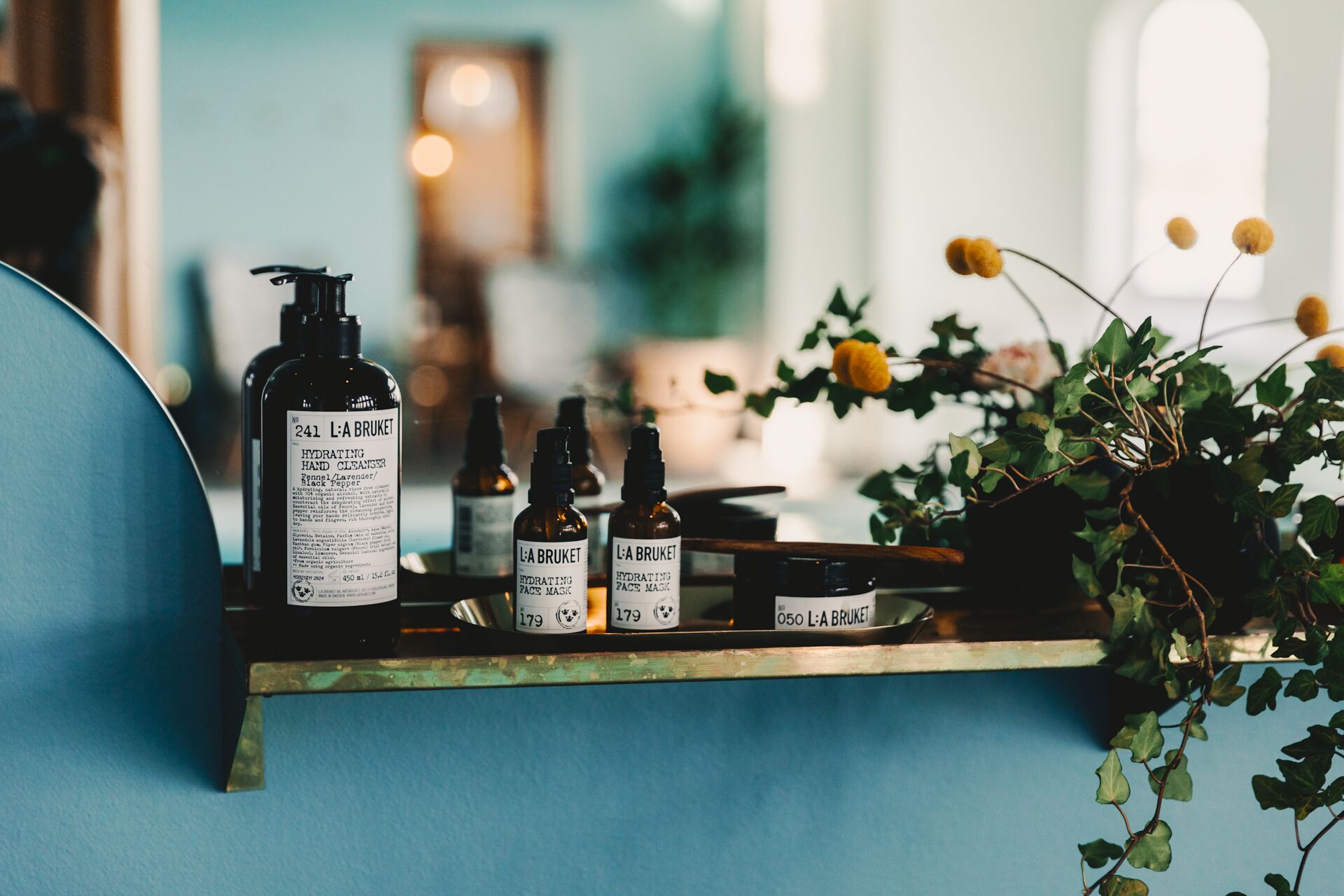 A shelf with various L'A BRUKET skincare products, including a hand cleanser and face mask.
