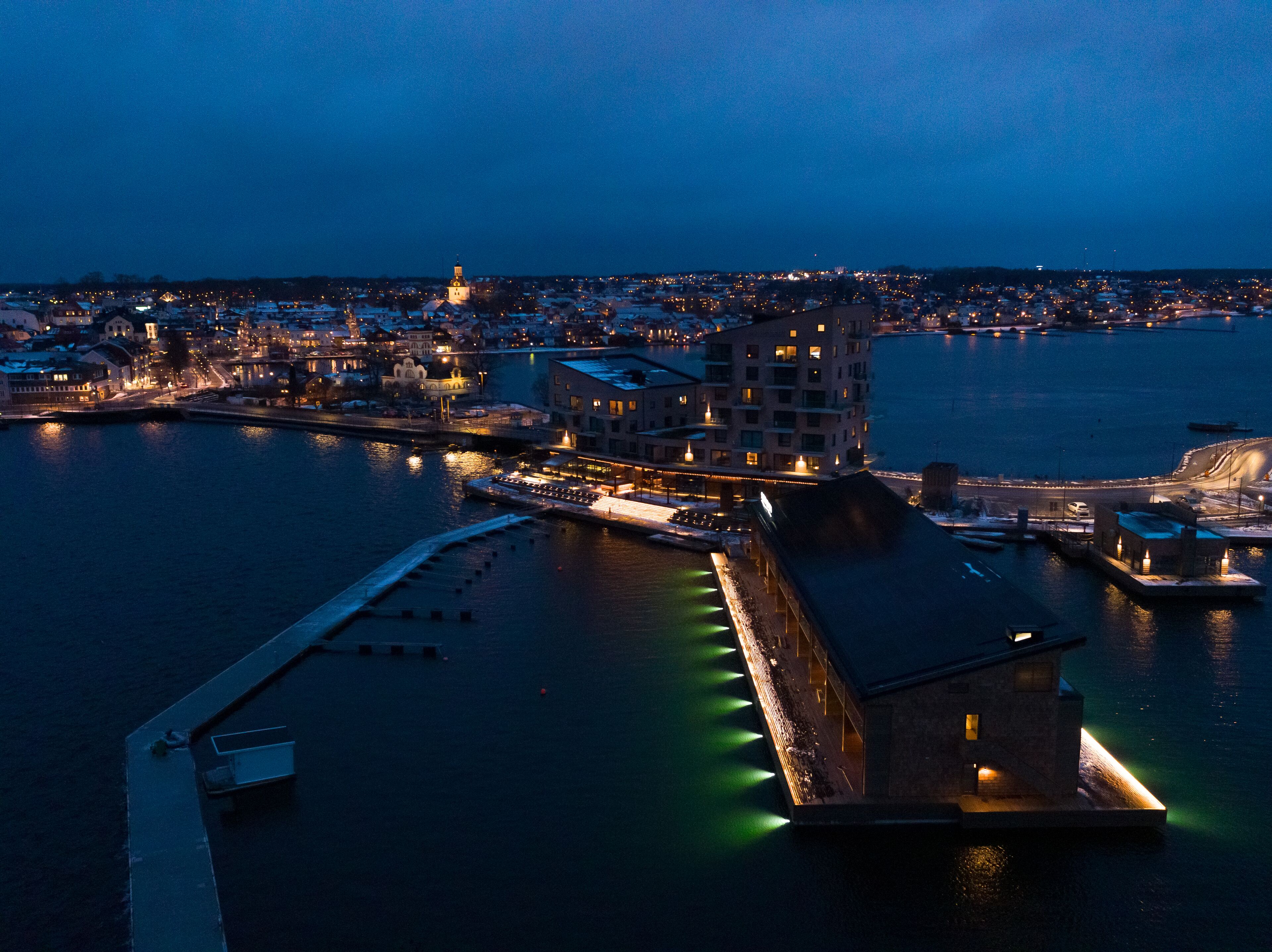 A waterfront hotel with a prominent building, a dock, and a pier.