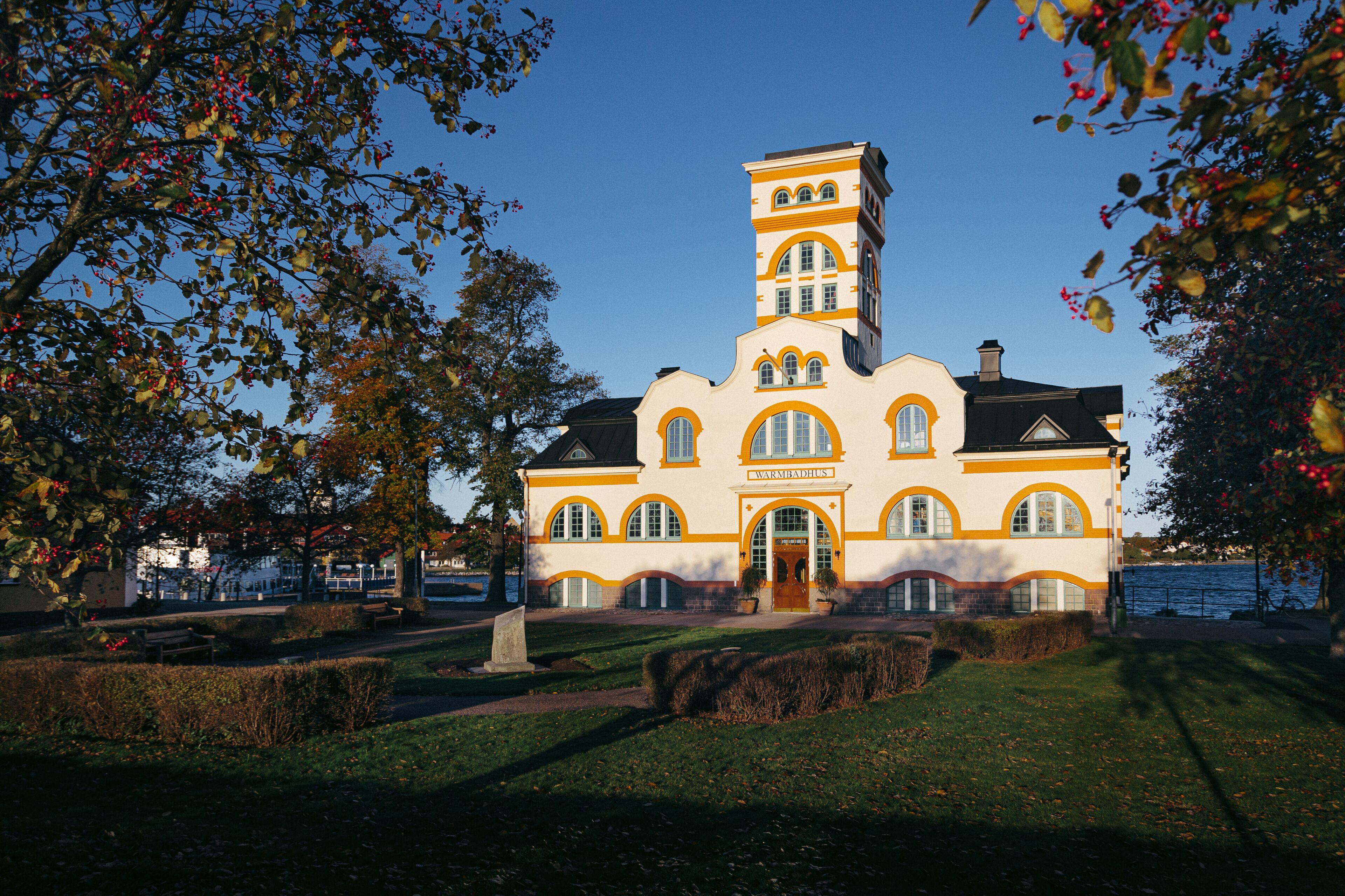 A large, historic building with a prominent tower, arched windows, and a well-maintained lawn.