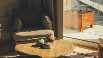 Una sala de estar moderna con un sofá, una mesa de centro con jarrones decorativos y vistas a un edificio a través de una ventana.