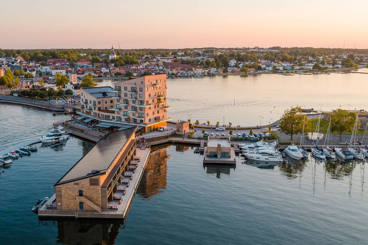 A waterfront property with a dock, a building with multiple floors, and a marina with boats.