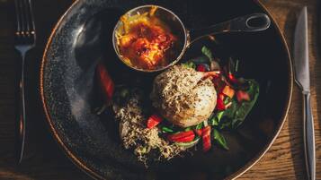 Un plato con ensalada, una porción de salsa y un trozo de carne sobre un plato oscuro.