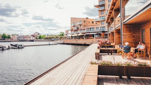 A waterfront property with a wooden deck, outdoor seating, and a view of the water. - Slottsholmen hotell och restaurang (Vastervik)