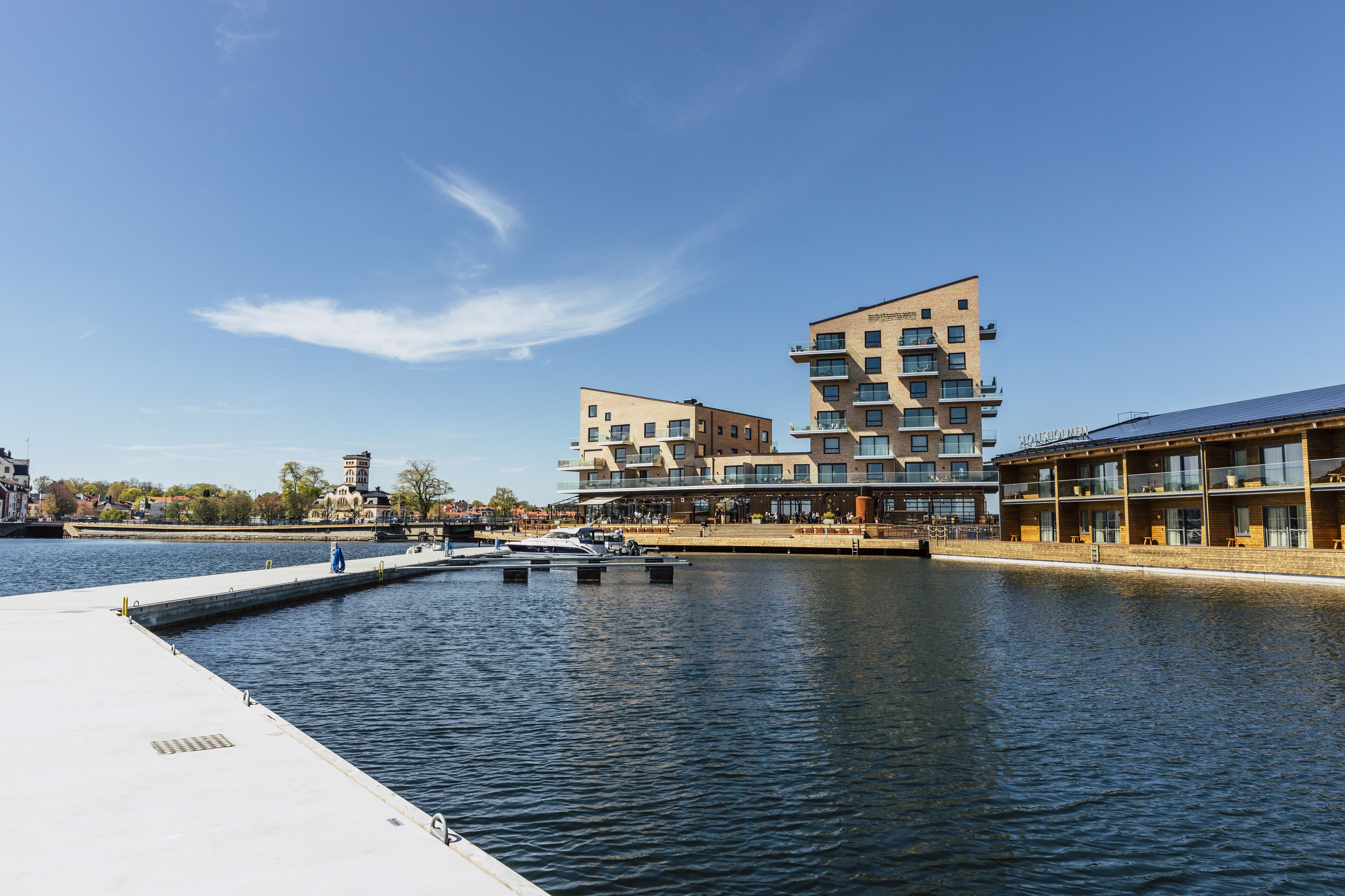 A waterfront hotel with modern architecture, a dock, and a canal.