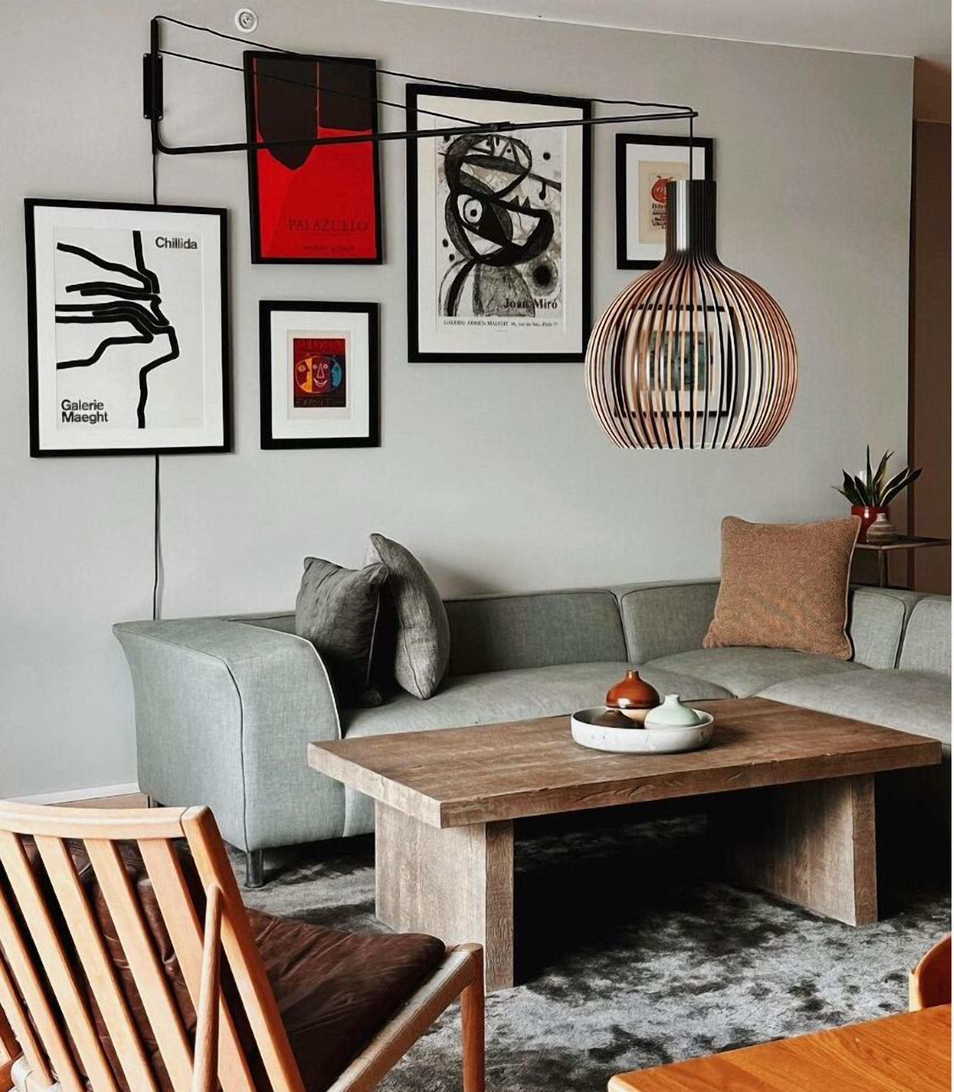 Una sala de estar moderna con un sofá gris, una mesa de centro de madera y cuadros enmarcados en la pared.