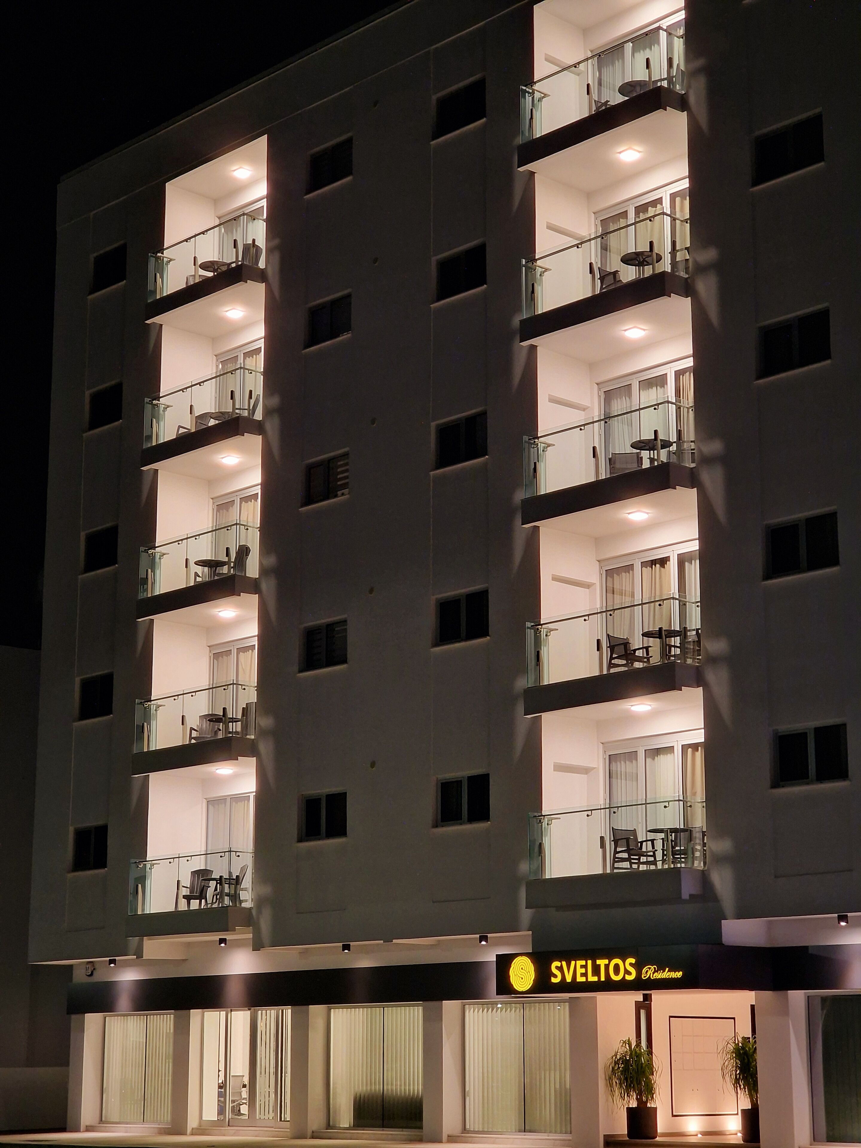 Un hôtel à plusieurs étages doté de balcons, une enseigne indiquant « SVELTOS Residencia », et une architecture moderne.