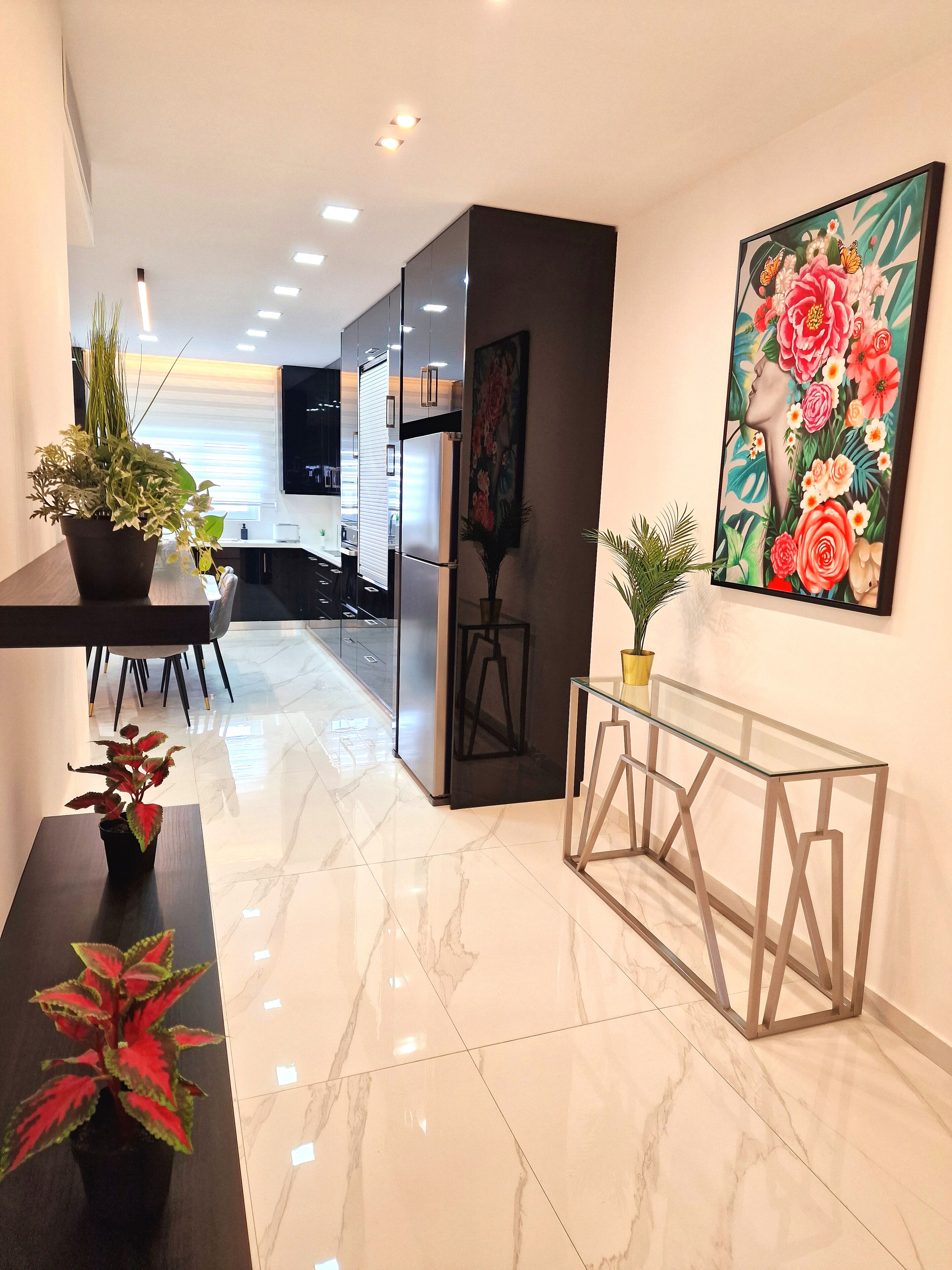 Un interior moderno con suelo de mármol, una consola de cristal y una planta en maceta.