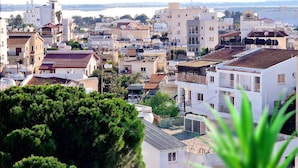 A cityscape with buildings, a body of water, and a potted plant in the foreground. - Sveltos Residence 3Bedroom Suites (Larnaca)