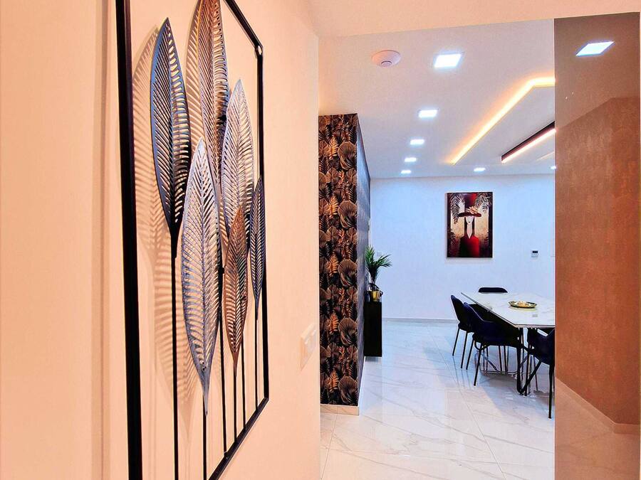 A modern interior with a dining area, a wall-mounted art piece, and a ceiling with recessed lighting.