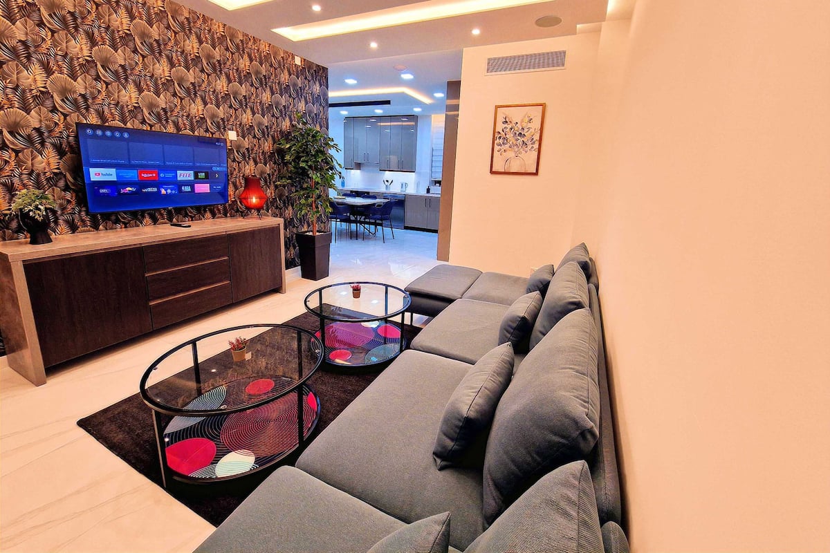 A modern living room with a sofa, a TV, and a decorative wall.
