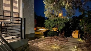 A nighttime outdoor area with a paved walkway, a metal railing, and a tree. - The Cottage-Historical Home Valley Views! (S) (Ogden)