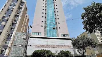 A tall building with a central glass facade and multiple floors.