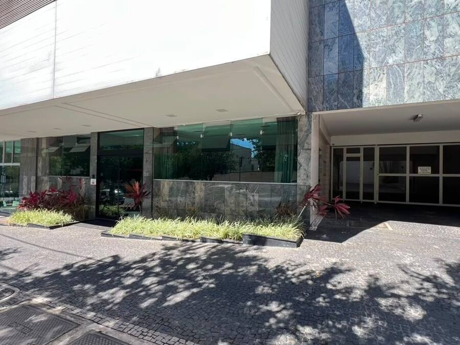 A modern building with a covered entrance, large windows, and a paved area with planters.