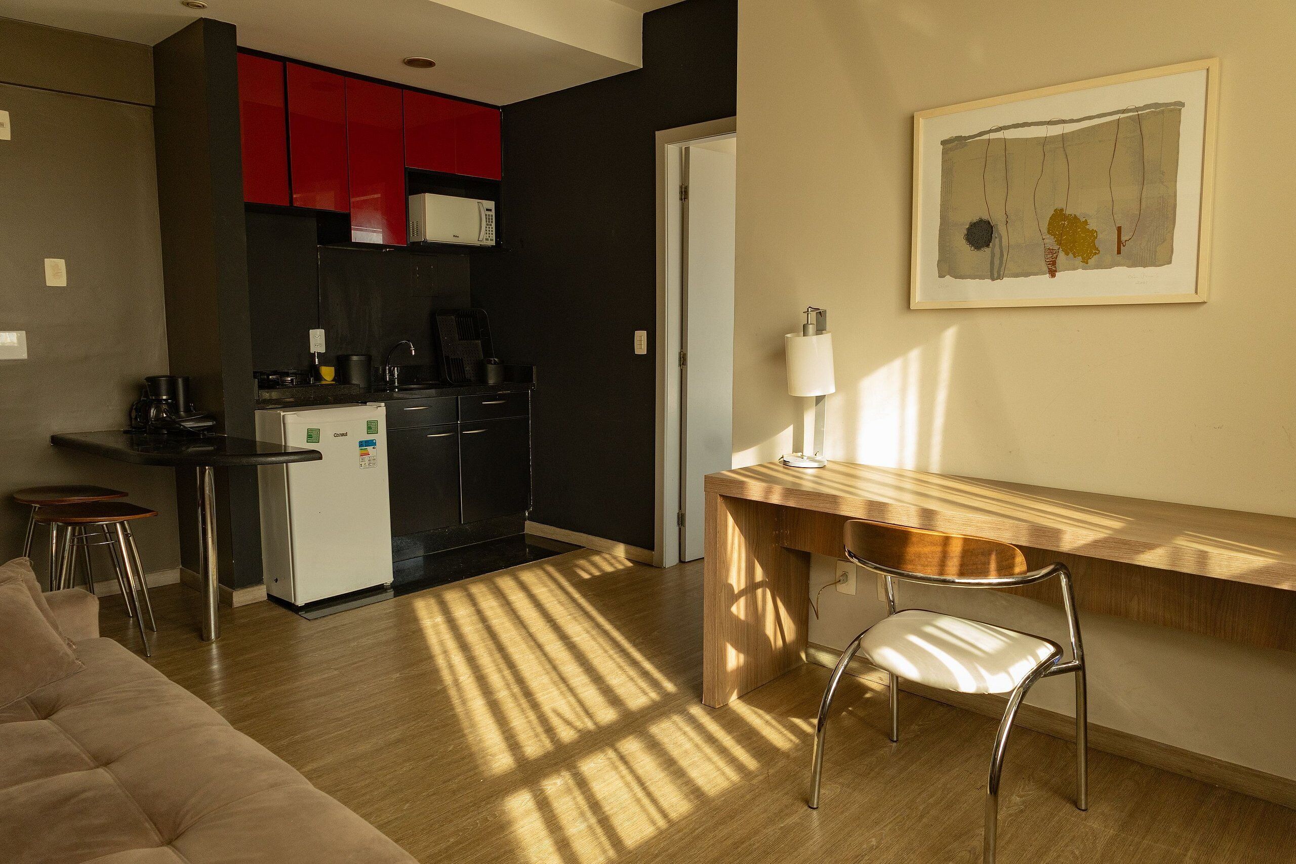 Una cocina moderna con armarios rojos, un refrigerador blanco y una mesa de comedor de madera con una silla.
