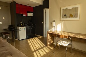 A modern kitchen with red cabinets, a white refrigerator, and a wooden dining table with a chair. - Locking´s Barro Preto 4 (Belo Horizonte)