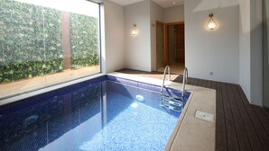 A modern indoor swimming pool with a clear view of the surrounding greenery through large windows. - Gladiolus Hotel (Jeddah)
