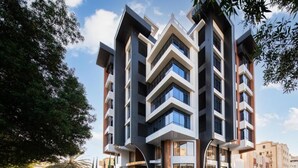 A multi-story hotel with a modern design, featuring a central entrance and parking area. - Gladiolus Hotel (Jeddah)