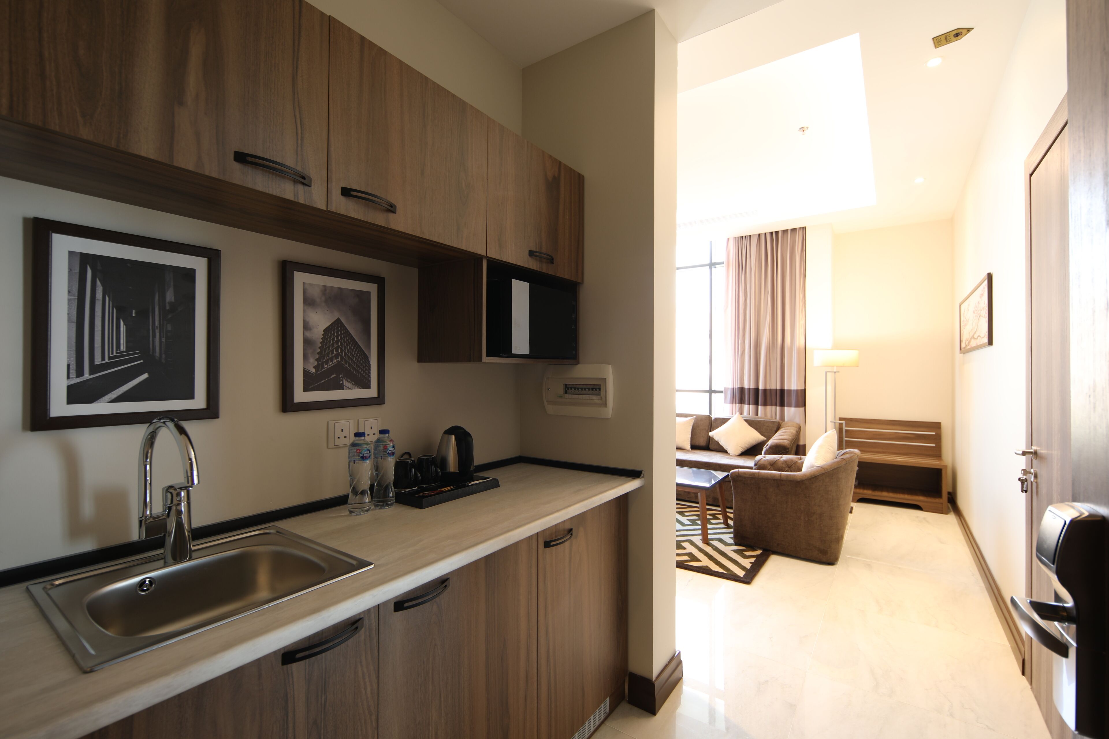A modern kitchen with a stainless steel sink, wooden cabinets, and framed artwork on the wall.
