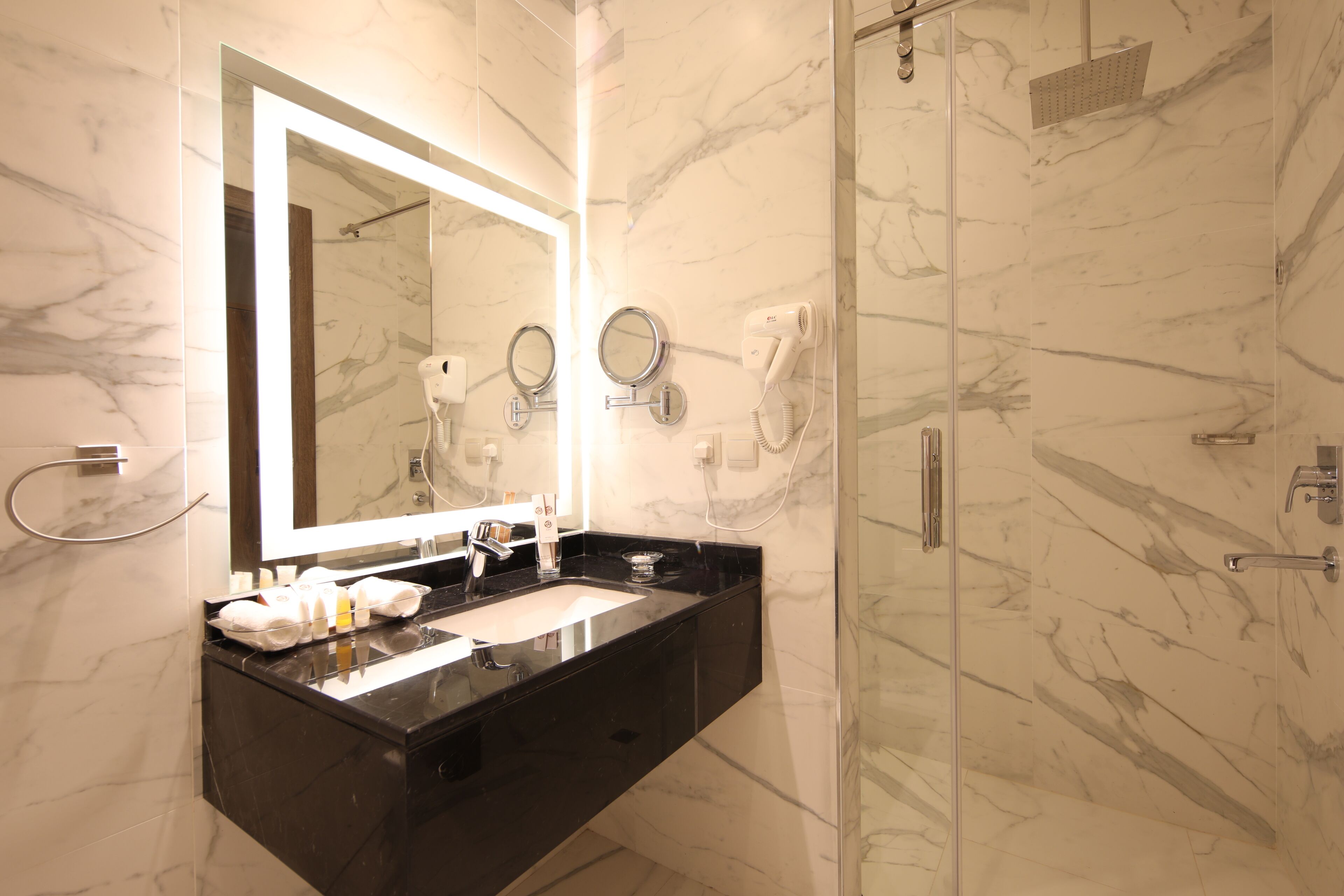 A modern bathroom with a black countertop, a large mirror, and a glass-enclosed shower.