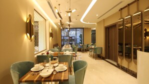 A dining area with multiple tables and chairs, a large window with a view, and a modern interior design. - Gladiolus Hotel (Jeddah)