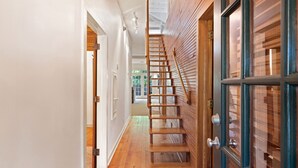 A wooden staircase leading to a second floor, a door with glass panels, and a hallway with wooden flooring.