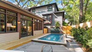 A modern house with a swimming pool, wooden deck, and outdoor seating area.