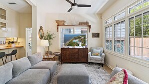 A living room with a sofa, ottoman, wooden cabinet, and a television.