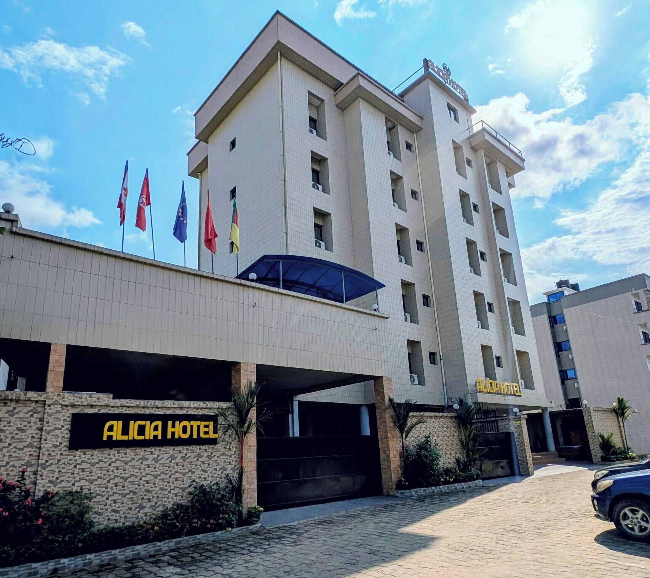 Een hotel met een bord waarop 'Alicia Hotel' staat en een overdekte ingang.