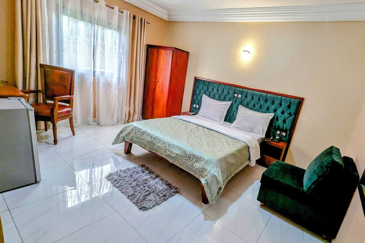 A neatly arranged bedroom with a bed, a chair, a desk, and a mirror.