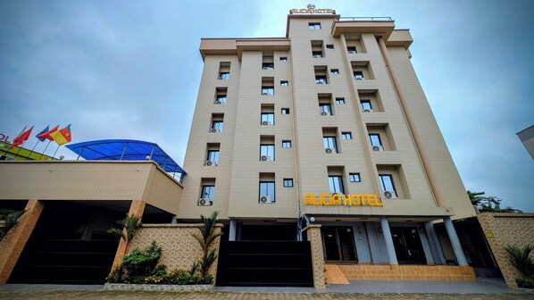A hotel with a modern design, featuring a prominent entrance with steps and a sign. - Alicia Hotel (Douala)