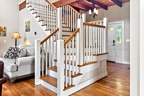 A staircase with white railings and wooden steps, a lamp, a couch, and a door with a window.