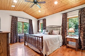 A bedroom with a wooden ceiling, a bed with a headboard, a nightstand, a lamp, and curtains. - Fireside Retreat | Pet-Friendly, Hot Tub, Game Area & Fire Pit! (Black Mountain)